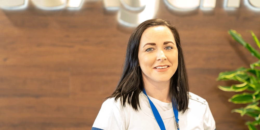 A photo of Mhari smiling below a 'FreeAgent' sign in the FreeAgent office.