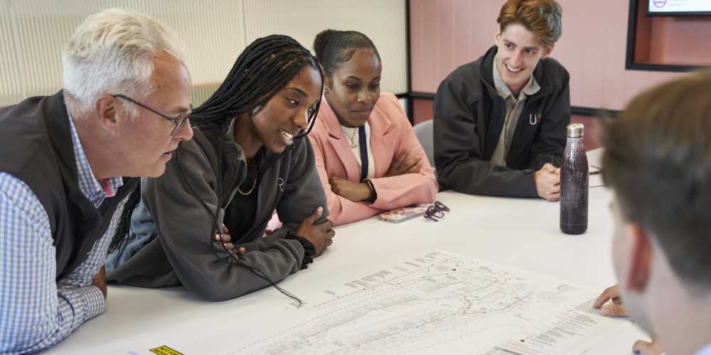 Photo of 5 Utility Results employees sitting round a table and looking at an infrastructure map.