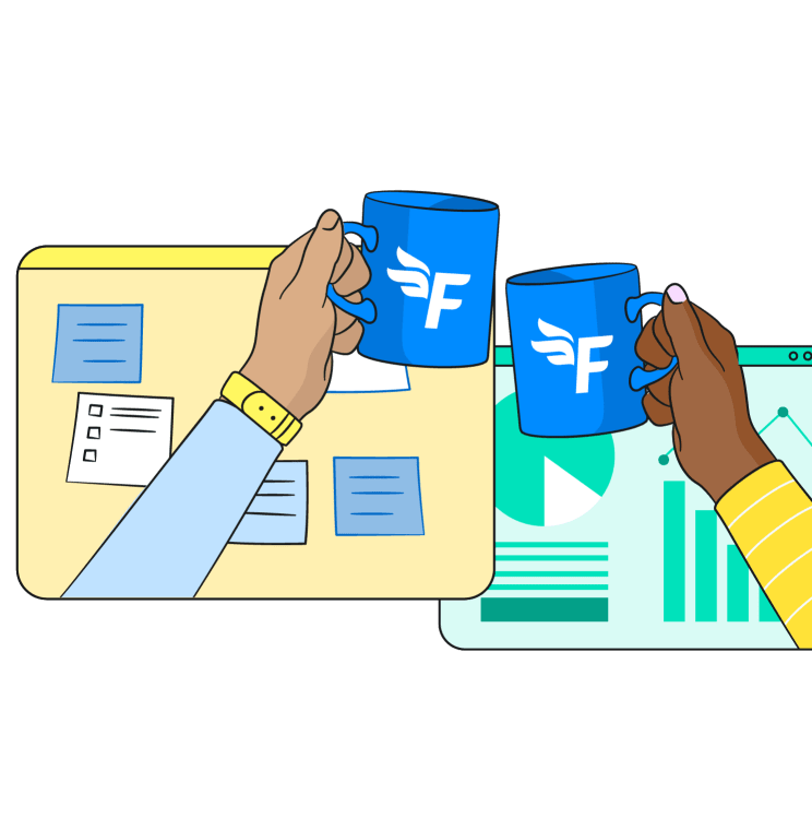 Two people clinking mugs together in front of two computer screens.